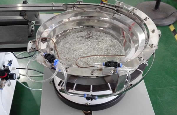 Vibrating bowl feeds components automatically.